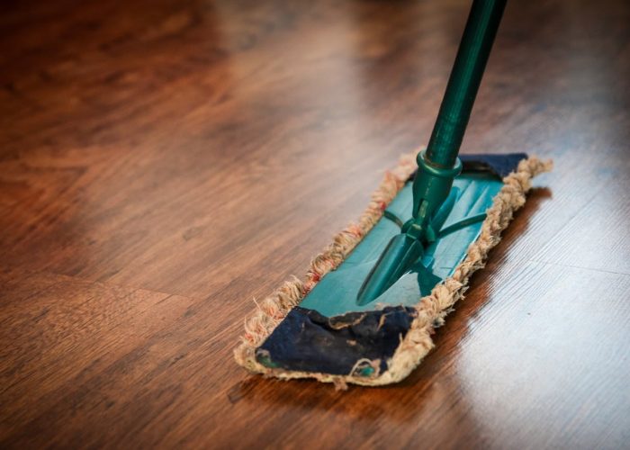 A detailed view of a mop cleaning a wooden floor, showing texture and pattern.